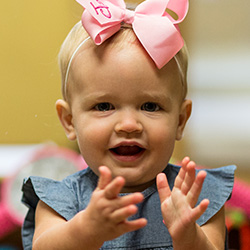 infant smiling with pink bow