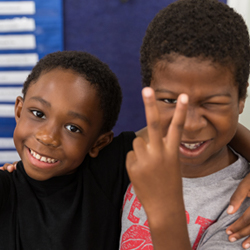 two boys smiling and giving the peace sign