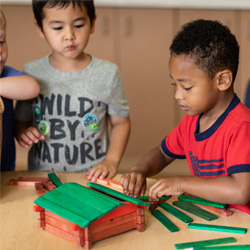 two boys building a house with wood blocks