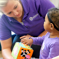 Teacher assisting a preschool child with a hands-on learning activity