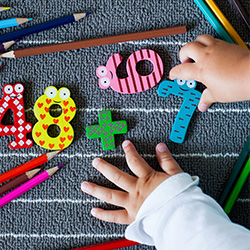 little kid hands playing with block letters on carpet