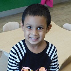 Smiling preschool child sitting at a classroom table