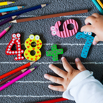 little hands playing with number blocks and pencils
